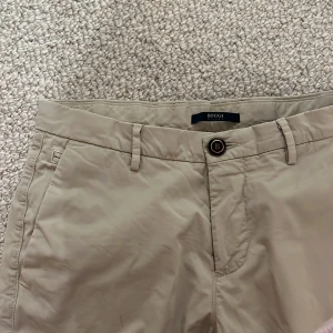 Beiga chinos från Boggi Milano - Snygga beiga chinos från Boggi Milano med klassisk rak passform. Tillverkade i mjuk bomull som funkar året om. NYPRIS: 1990