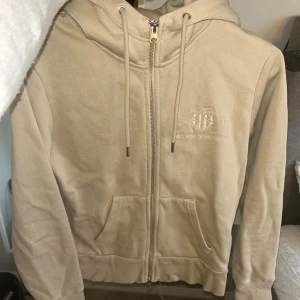 Beige Gant hoodie med zipp - En beige Gant hoodie med zipp hela vägen ner, väldigt skönt och mjuk på insidan. Även väldigt lätt att styla.💕 Använd max 3-4 gånger.💕