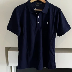 Marinblå Polo Piké  - Säljer denna helt nya, riktigt fina Polo Ralph Lauren piké med storleken S. Skriv gärna vid intresse och för mer info!