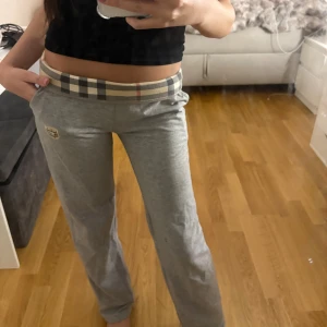 Grå byxor med fina detaljer - Snygga grå mjukis byxor som är bekväma och låga i midjan. Väldigt fina detaljer med burberry tryck osv, utgår dock från att de ej är äkta då de är köpta för flera år sedan och därför inte heller kommer ihåg vart de är köpta. Använts ett par gånger och därför har några mindre slitningar men annars i fint skick. Passar storlekarna Xs och Xxs
