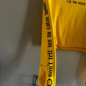 Gul croppad sweatshirt Madlady S/M - Gul croppad sweatshirt från Madlady x Lisa Anckarman med svart text 'i'm too much' på bröstet och 'don't tell me to calm down' längs ena ärmen. Mjuk och skön med rund hals och långa ärmar. Material: 80% bomull, 20% polyester.