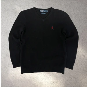 Svart ulltröja Polo Ralph Lauren - Klassisk svart tröja från Polo Ralph Lauren i 100% ull med v-ringning och röd broderad logga på bröstet. (Det som syns på tröjan på bilderna är damm och inte fläckar) lite luddig. skickar snabbt efter att du har beställt📦✅ storlek M😁