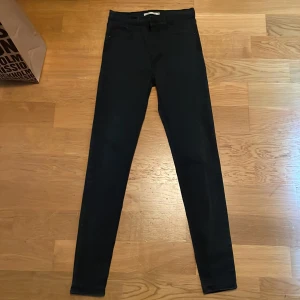 Svarta skinny jeans från Levi's - Svarta skinny jeans från Levi's med klassisk femficksdesign och Levi's-lapp bak i midjan. Byxorna har smal passform hela vägen ner och är tillverkade i stretchigt jeanstyg för en bekväm känsla. Perfekta för dig som gillar en tight och stilren look. Pris kan diskuteras 