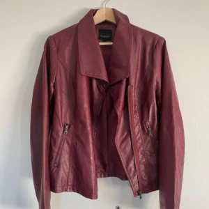 Röd/vinröd skinnjacka  - Cool röd/vinröd skinnjacka (inte äkta) i storlek 40 men mer som en M. Finns några mindre skador (se sista bilden) men inget som man märker eller ser när jackan är på. 