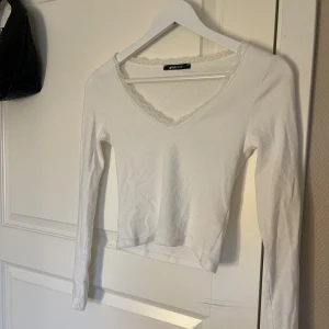 Vit ribbad långärmad topp Gina Tricot - Vit långärmad topp från Gina Tricot i ribbat material. V-ringad med spetskant runt halsen som ger en söt touch. Figurnära passform och enkel design som funkar till många olika stilar. Supersöt men tycker inte den passar mig, använd fåtal gånger.