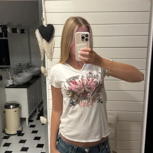 Vit t-shirt Zadig & Voltaire med tryck - Cool vit t-shirt från Zadig & Voltaire med färgstarkt tryck framtill som har rockiga detaljer, stjärnor och eldflammor. T-shirten har rund hals och korta ärmar, tillverkad i mjuk bomull. Perfekt för dig som gillar edgy och unik stil. Perfekt till ljus blåa jeans❣️❣️ aldrig använt för liten för mig