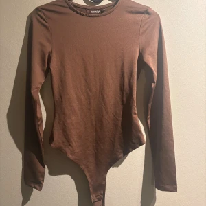 Brun body från Nelly  - Brun string body från Nelly i storlek xxs, säljer då den är lite för liten för mig. Den sitter jättefint på och är super skön. Använd en gång så väldigt bra skick:) Hör av er om ni har några frågor, priset kan även diskuteras. Köparen står för frakten😊❣️