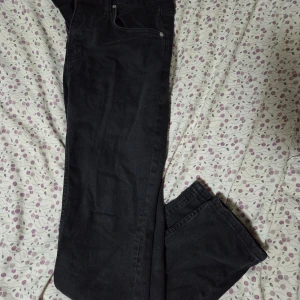 Svarta jeansbyxor från 157, storlek M - Svarta jeansbyxor från 157 i klassisk femficksmodell med dragkedja och knapp framtill. Byxorna har rak passform och är tillverkade i mjukt jeanstyg som sitter skönt. Perfekt för dig som gillar stilrena och enkla svarta jeans.