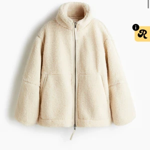 Beige teddyjacka med dragkedja - Mysig teddyjacka i beige med hög krage och två stora fickor framtill. Jackan har en rak och loose passform, tillverkad i fluffigt fleece-material och stängs med dragkedja. Perfekt för kalla dagar när du vill vara både varm och snygg.