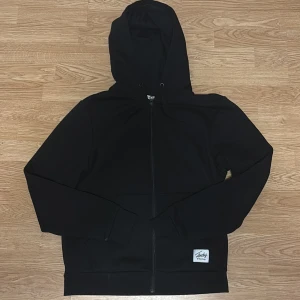 Svart hoodie med dragkedja från Andy - Klassisk svart hoodie från Andy med hel dragkedja framtill och huva med snörning. Hör av vid intresse!