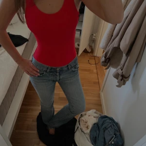 Röd body med öppen rygg - Snygg röd body med klassisk form och breda axelband. Materialet är ribbat och ger en cool textur. 