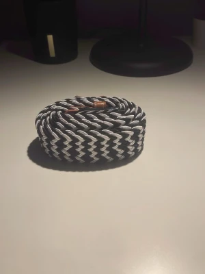 Svartvitt flätat bälte med silverfärgat spänne - Snyggt svartvitt flätat bälte med silverfärgat metallspänne och detaljer i brunt konstläder. Bältet har ett mönster av zick Zack. Bältet är helt ny. 