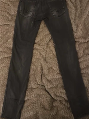Replay jeans Anbass  - Snygga svarta gråa  jeans med diskreta slitningar och klassiska bakfickor med dekorativa sömmar. Jeansen har en smal passform och är perfekta för en trendig look. Materialet är jeans och färgen är mörk grå