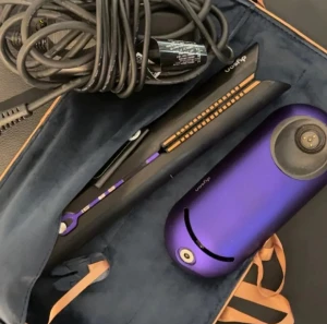 Dyson Corrale plattång med fodral - Säljer en Dyson Corrale plattång i svart och lila med tillhörande värmeskyddande fodral och laddare. Plattången har flexibla plattor och en modern design. Perfekt för att styla håret smidigt och effektivt. Fodralet är i mjuk sammet med beige band. Ordinarie pris 5100kr