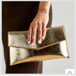 Guldig kuvertväska med kedja - Säljer en snygg kuvertväska i guld, finns även en kedja till✨ Väskan har en stilren design med ett triangelformat lock och passar perfekt till festliga tillfällen. Enkel att bära både i handen och över axeln.✨ Använd en gång🩷🩷