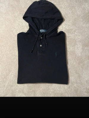 Mörkblå hoodie från Polo Ralph Lauren - Mörkblå hoodie från Ralph Lauren, använt skick! Lagat vid ena armen men syns inte jättemycket, därav priset! ✨🤗