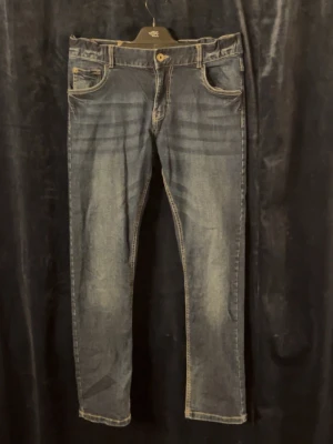 Blå straight jeans med slitningar - Ett par klassiska blå jeans med snygga slitningar och tvättade detaljer. Modellen har raka ben och fem fickor, samt kontrastsömmar. Perfekta till vardagslooken och passar till allt. Skriv för frågor (storlek 164)