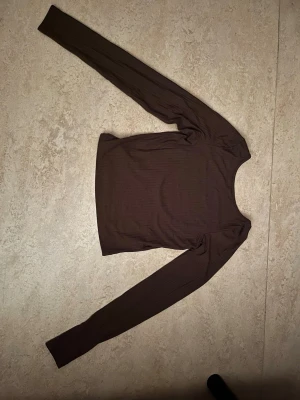 Brun långärmad topp - En brun långärmad topp med rund halsringning och ribbad struktur. 