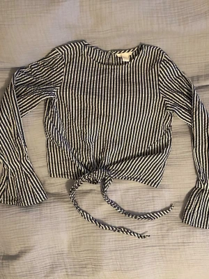 Randig blus med knyt i midjan och utsvängda ärmar - Säljer en snygg blus med blåvita ränder och långa bootcut ärmar. Toppen har ett knytband i midjan som är en skitsnygg detalj. (Banden är inte knutna utan knyts själv) skriv om ni undrar om något 💕(läs min profil)