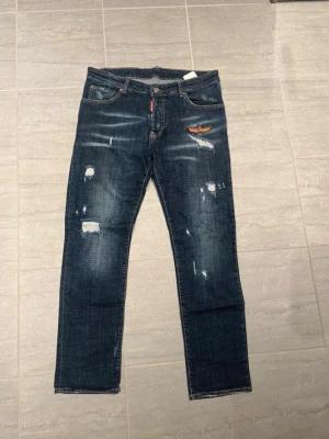 Mörk blåa Dsquared 2 slitna jeans W30/strl:48 - 100% äkta!!! Mycket bra skick, knappt använda. Dsquared2 jeans i mörkblå denim med slitna detaljer och tvättad finish. Snygg och trendig passform med tydliga Dsquared2-detaljer som ger en exklusiv look. Jeans som sticker ut och passar både vardag och fest. Storlek 48. Vid frågor eller funderingar, kontakta mig!👊😃