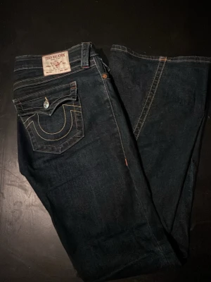 Mörkblå True Religion jeans - Snygga mörkblå jeans från True Religion med ikonisk kontrastsöm och dekorativ bakficka med lock och knapp. Klassisk femficksmodell i robust jeansmaterial. Perfekta för dig som vill ha en tidlös och streetinspirerad look. Inga defekter vid frågar är de bara att skriva💕ny pris 1300kr