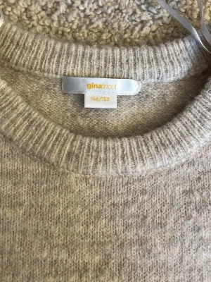 Beige stickad tröja Gina Tricot - Mysig beige stickad tröja från Gina Tricot med rund halsringning och ribbade muddar. Tröjan har en enkel och stilren design som passar perfekt till höst och vinter. Materialet känns mjukt och skönt mot huden.