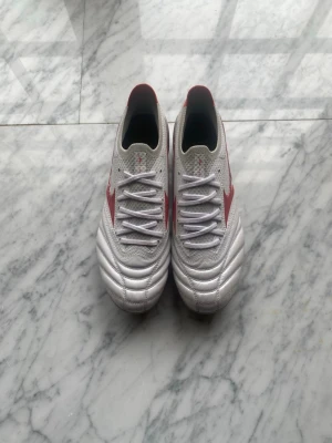 fotbollsskor  - Säljer ett par vita Mizuno Morelia made in Japan fotbolls skor med SG dobbar, köpta för 4000kr. Helt oanvända skor som är handgjorda från Japan med känguru läder. Skickar med boxen.