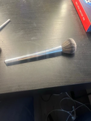 F03 blush Silver sminkborste från Caia - Snygg sminkborste från Caia med silverfärgat handtag och mjuka, täta borst i beige och brunt. Perfekt för applicering av puder, bronzer eller rouge. Handtaget är i metall och borsten har en klassisk rundad form som gör det enkelt att få ett jämnt resultat.