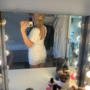 Vit kort puffärmad klänning/ studentklänning - Supersöt vit kort klänning med puffärmar och rynkade detaljer. Klänningen har en öppen rygg och är figurnära med en snygg passform. Passar perfekt som studentklänning!🥰