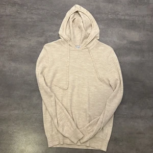 Beige hoodie från Ahlquist Clothing - Säljer en väldigt snygg och stilren beige hoodie från Ahlquist Clothing i storlek S för 300 (ordinarie pris 999). Tröjan har huva med snörning och är tillverkad i merinoull. Perfekt för dig som gillar en clean och enkel stil. Långärmad och med relaxed passform. 