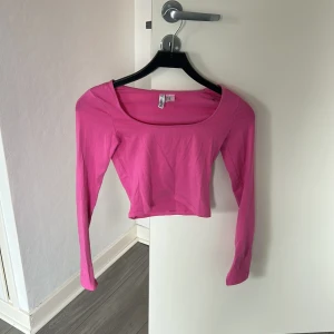 Rosa croppad långärmad topp - Snygg rosa croppad topp från HM med lång ärm och bred, rundad urringning. Perfekt att styla med höga jeans eller kjol för en trendig look. Tunn och mjuk bomullskvalitet som känns skön mot huden.