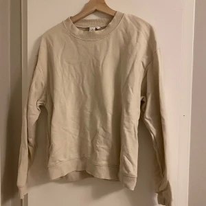 Beige sweatshirt från Monki - Enkel och stilren beige sweatshirt från Monki i storlek M. Tröjan har rund halsringning, ribbade muddar och är tillverkad i mjuk bomull. Perfekt för en chill och avslappnad look.