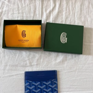 G-plånbok  - Snygg och stilren i blå med deras ikoniska mönster. Plånboken har flera kortfack och är tillverkad i skinn med tryckt logga framtill. Perfekt för dig som vill ha något exklusivt och smidigt i fickan.  