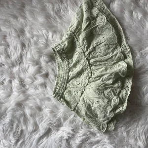 Ljusgrön broderad kortkjol från Zara - Supersöt ljusgrön kortkjol från Zara med broderade blommor och spetsdetaljer. Kjolen har en elastisk midja och volangkant som ger en extra feminin vibe. Perfekt för dig som gillar romantiska och detaljerade plagg.