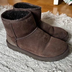 Bruna UGG skor - Mysiga bruna UGGs. Väl använda men fortfarande så fina, är tunnt på en av ”tårna” men går nog lätt att fixa om man bara limmar dit lite eget fluff!❤️passar 38-39