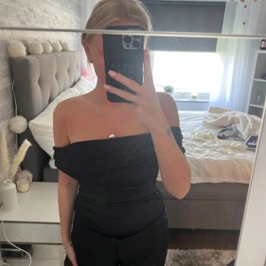 Svart offshoulder body från hm - Säljer en svart offshoulder body med tight passform. Toppen har en stilren och enkel design utan synliga detaljer och är perfekt för dig som gillar minimalistisk stil.