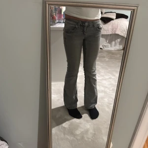 Grå bootcut jeans med låg midja - Säljer ett par grå jeans med bootcut-modell och låg midja. Jeansen har klassiska fickor fram och bak, med snygga detaljer på bakfickorna. Perfekta om du gillar ett par jeans som sitter tajt upptill och släpper vid vaden. Säljer då jag helt enkelt tömmer gaderoben. strl 152 och säljer för 100kr då jag känner själv att det är svårt att hitta bra jeans för litet pris. 