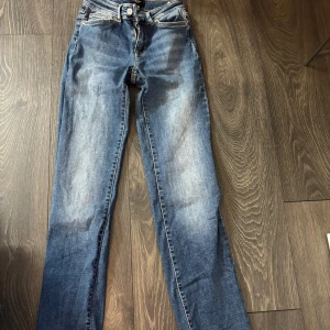 Blå jeans från Vero Moda - Snygga blå jeans från Vero Moda i klassisk denim med lätt slitna detaljer och raka ben. Modellen har normal passform och fem fickor. Perfekta till en avslappnad stil och funkar året runt. Använda ett fåtal gånger.