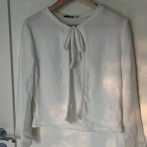 Vit långärmad tröja med knyt från 157 - Vit långärmad tröja från lager 157 med snygg knytning framtill vid halsen. Enkel och stilren design. Knappt använd.