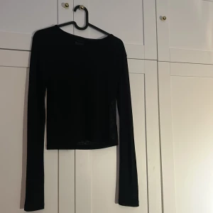Svart croppad långärmad topp - En svart, enkel och croppad långärmad topp med rund hals. Den är lite genomskinlig så jag brukar ha ett svart linne under. Använd väldigt lite