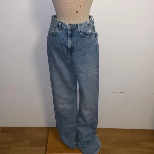 Wide highrise jeans från Zara - Snygga ljusblå jeans från Zara i modell med breda ben och råa, fransiga benslut. Hög midja och slits vid bensluten 