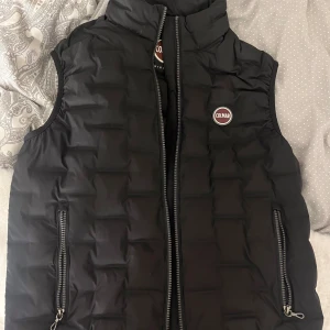 Svart dunväst från Colmar Originals - Snygg svart dunväst från Colmar Originals med quiltad design och två dragkedjefickor framtill. Köpt för 2799kr. Använd endast 2 gånger. Storlek 46 men passar en XS-S. Skriv för fler bilder eller funderingar