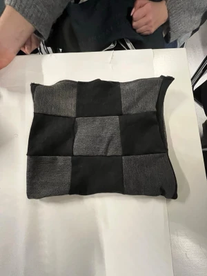 Svart och grårutigt datorfodral - Säljer ett unikt datorfodral med rutigt mönster i svart och grått. Väskan har en boxig form och är sydd i mjukt tyg, perfekt för dig som gillar att sticka ut med stilrena detaljer. Passar dig som vill ha något annorlunda och coolt.