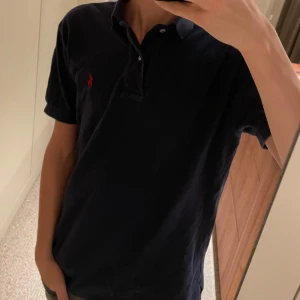 Blå piké från Ralph Lauren - Säljer nu denna sjukt fräscha Ralph Lauren piké som funkar till festligheter men likaså skola/jobb. Modellen är 180 och väger ca 62 kg. Tröjan är lite för stor och skulle rekommendera den till någon lite större än modellen. Pikén är i mycket bra skick. Skriv för frågor eller vid behov av bilder! Pris ej hugget i sten