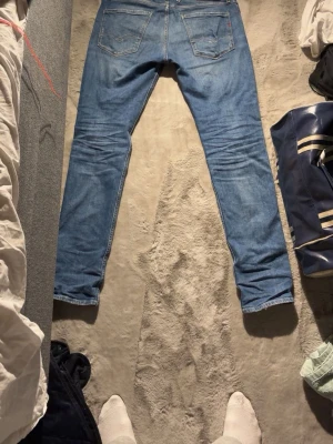 Replay Anbass slim fit jeans blå - Säljer ett par blå Replay Anbass jeans i slim fit med klassisk femficksdesign och slitna detaljer. Jeansen har normal midja och är gjorda i ett mjukt jeanstyg som sitter snyggt på benen. Perfekta för dig som gillar en modern och stilren look.