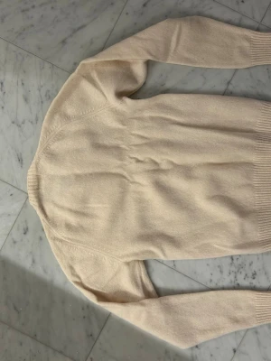 Beige stickad tröja från Uniqlo - Säljer en mjuk och stilren beige stickad tröja från Uniqlo. Tröjan har rund hals, långa ärmar och ribbade muddar vid ärmslut och nederkant. Perfekt för lager-på-lager och enkel att matcha med jeans eller chinos. Tröjan är som ny