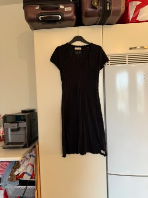 Svart stickad kortklänning  - Svart stickad klänning med korta ärmar och v-ringad hals. Klänningen har ett snyggt hålmönster i zigzag och är lätt utställd från midjan. Perfekt för dig som gillar en enkel men ändå cool look. Materialet är mjukt och skönt stickat. Från märket Odd Molly. Storlek 2 som enligt deras storleksguide motsvarar en M. Mycket fint skick, jag hittar inga synliga anmärkningar eller defekter.  