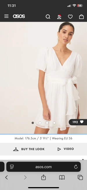 Vit kort omlottklänning med puffärm - Superfin vit kort klänning med puffärmar, omlottliv och bred knytdetalj i midjan. Klänningen har v-ringning både fram och bak samt lätt struktur i tyget som ger en luftig känsla. Perfekt för sommarens alla tillfällen!