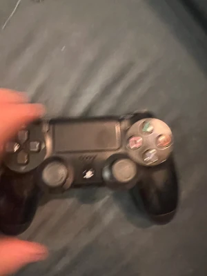 PlayStation DualShock 4 - Svart PlayStation DualShock 4-kontroll till PS4. Kontrollen visar tecken på användning med viss slitage på knappar och baksida, men ser ut att vara fullt fungerande. Perfekt för extra spelare eller som ersättningskontroll.