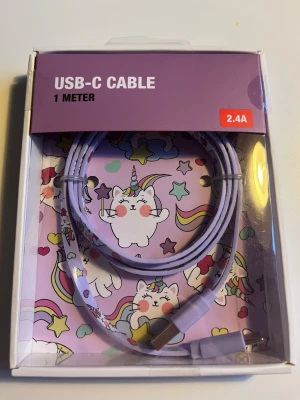 USB-C Cable 1 Meter Unicorn Cat - Söt USB-C kabel på 1 meter med unicorn-kattmotiv. Stödjer laddning upp till 2.4A och dataöverföring. Perfekt för laddning och synkronisering av kompatibla enheter. Levereras i originalförpackning, ser oanvänd ut och utan synligt slitage.